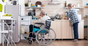 elderly couple in kitchen man in wheelchair in front of fridge