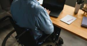 Man in wheelchair working on computer on a desk