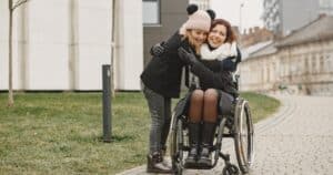 Girl giving a hug to a woman in wheelchair