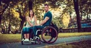 couple in wheelchair holding hands and looking at the camera