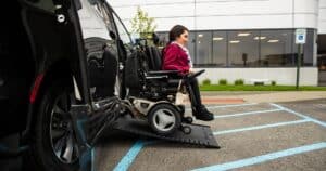 woman in wheelchair getting out of wheelchair van using ramp