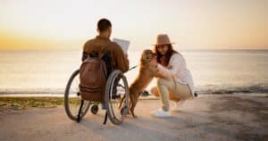 Couple with dog at the beach male on wheelchair