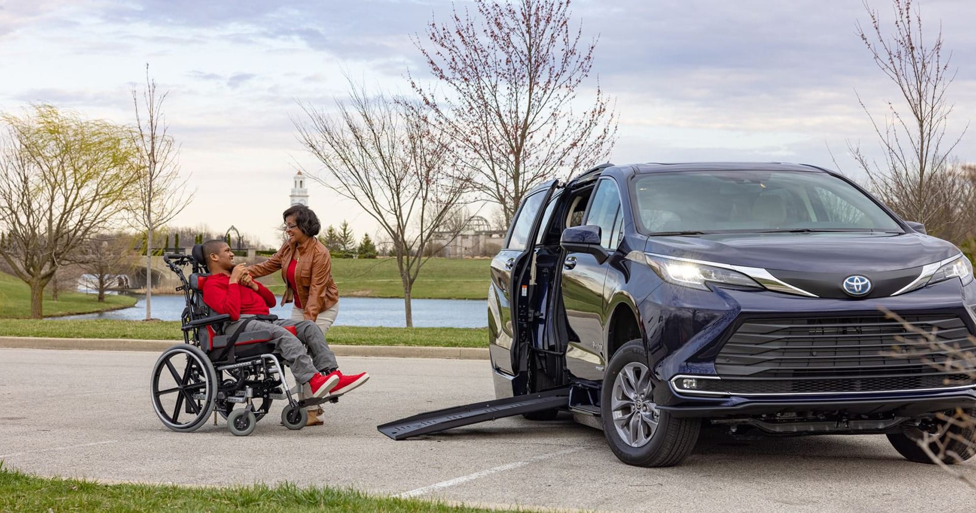 Woman smiling to son in wheelchair near Toyota Sienna Hybrid wheelchair van