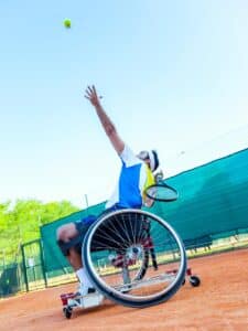 wheelchair tennis player with ball in the air